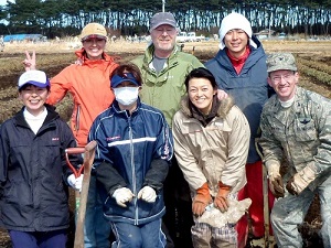 Lead faculty Brent Duncan, wearing the green jacket, his wife Penny, flashing the peace sign, and a U.S. Air Force task force helped clear tsunami debris from this strawberry field. Duncan's superb Japanese language skills were a huge asset to the project.  Also pictured is the Japanese family who live on the farm. Other photos on this page show the Shinto Gate in Noda Village standing amongst the destruction